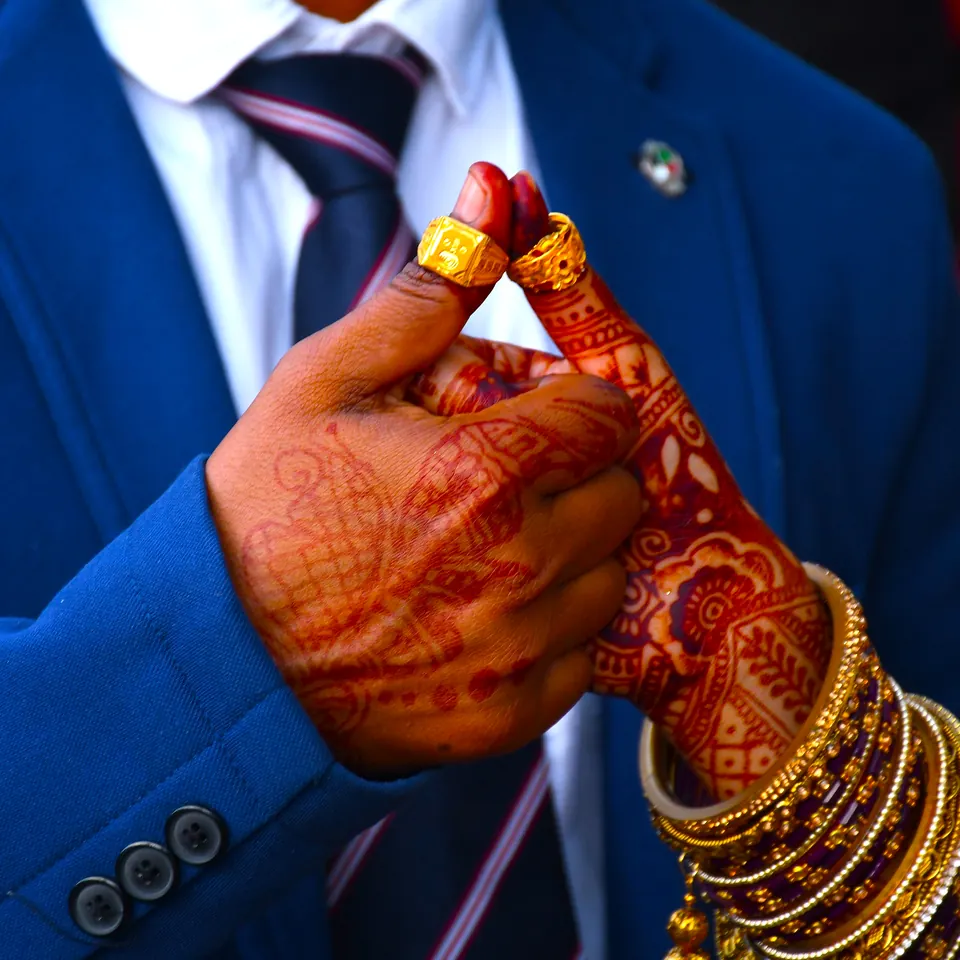 Bride and groom holding hands with traditional mehndi and jewellery