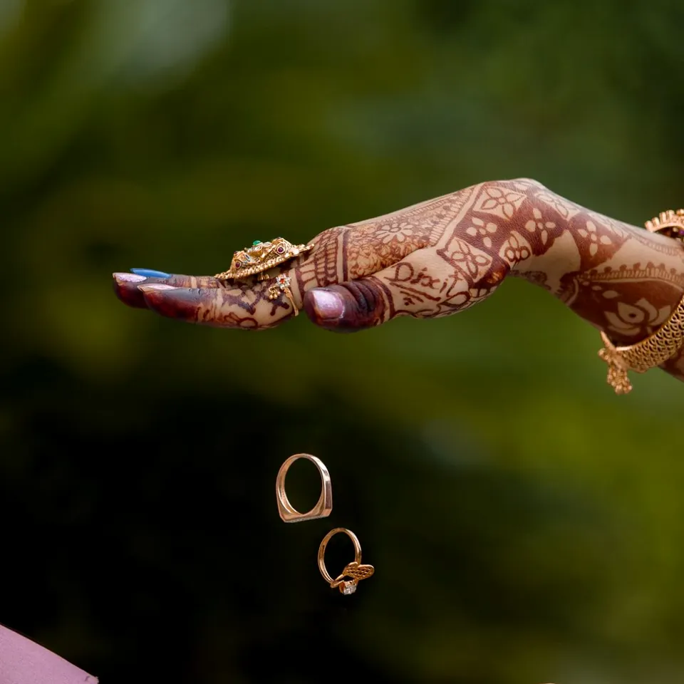 Wedding rings falling between the hands of a couple