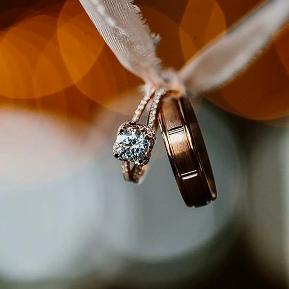 Wedding rings tied with a white ribbon against warm lights